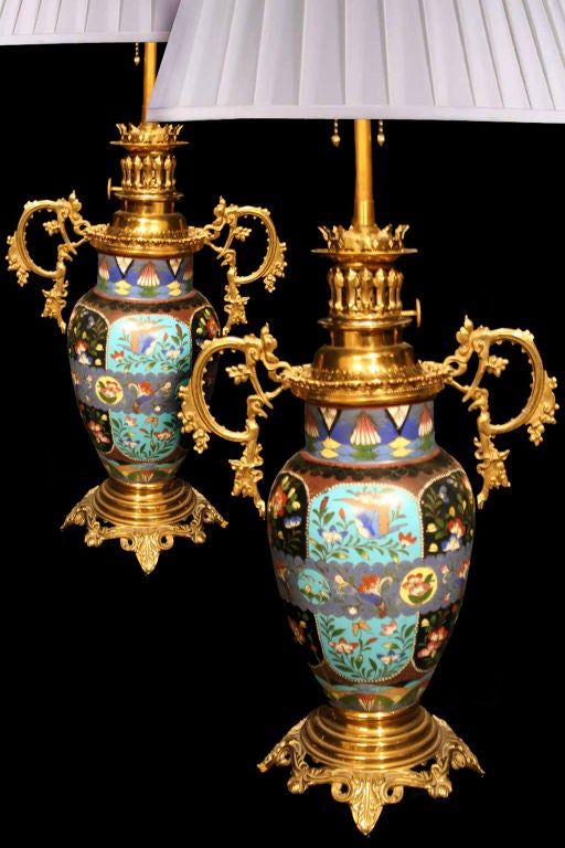 Pair French oil lamps, circa 1880.  Note the decorative brass mounts, including a Rococo pair of handles, collar and round footed base, which surround the Chinese cloisonné baluster form vase with polychrome bird and floral pattern decoration within