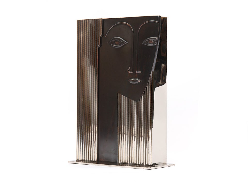 An asymmetrical base supports a chromed steel box fronted by a striking bronze face with chromed steel rod hair. In the style of Franz Hagenauer - circa 1960s. Can also function as a vase. Four available; priced individually.