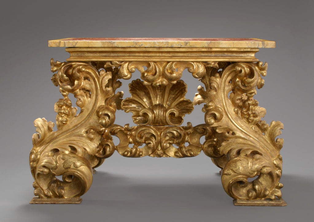 With a later red and sienna marble top, above the rectangular molded edge, on colossal S-scroll acanthus leaf legs joined by a conforming stretcher centered by a large scallop shell.  A similar table is illustrated, Gonzáles-Palacios, Il Tempio del