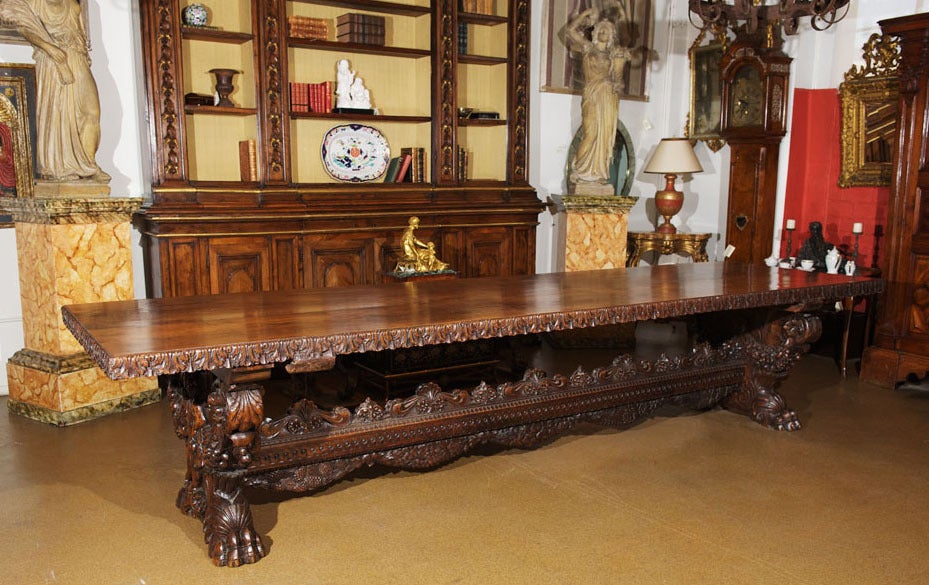 A late 18th century Italian Fratino table of exceptional patina, the top comprised of two solid ancient growth walnut planks, each 21" wide and 3 1/2" thick with the edges carved in acanthus leaf designs, supported by two massive trestle