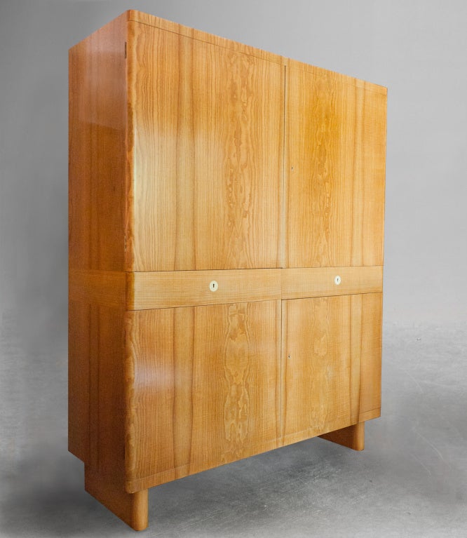 Large Swedish Art Deco cabinet by Axel Einar Hjorth designed while director of Nordiska Kompaniet (NK) Stockholm circa 1930's. Exterior is veneered in Ash-wood, has 4 doors and 2 drawers which are detailed with bakelite escutcheons. The interior