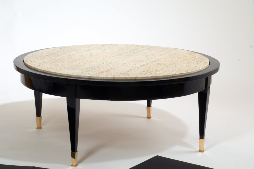Black lacquered round table with open travertine top and bronze sabots