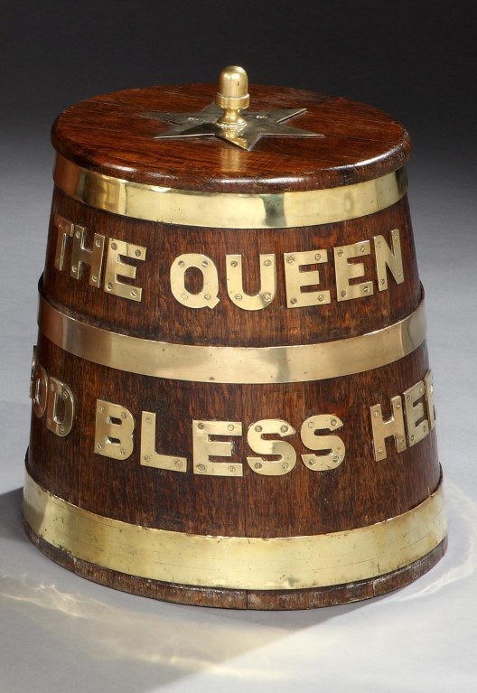 A rare Naval oak rum barrel or ‘Grog Tub’, formerly used aboard H.M.S Ganges, the main body with brass letters spelling out the ‘Royal Toast’, being ‘THE QUEEN GOD BLESS HER’, the heavy lid with brass finial and star detail. <br />
<br />
Notes: