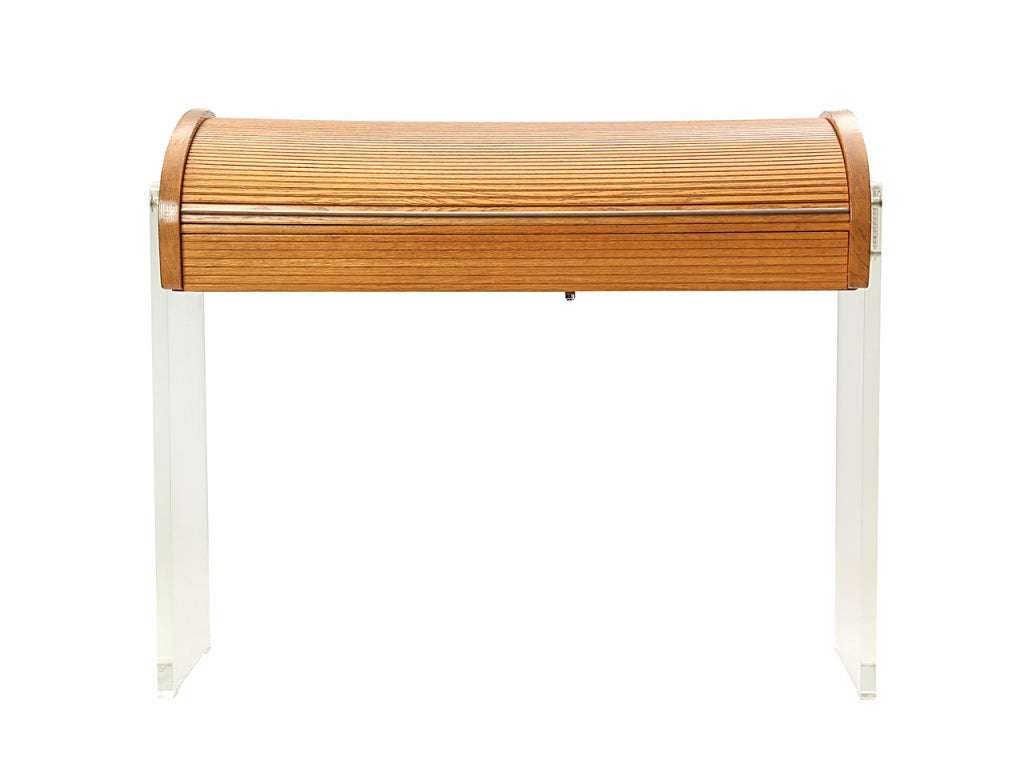 A roll-top writing desk in oak with lucite legs and leather writing surface.