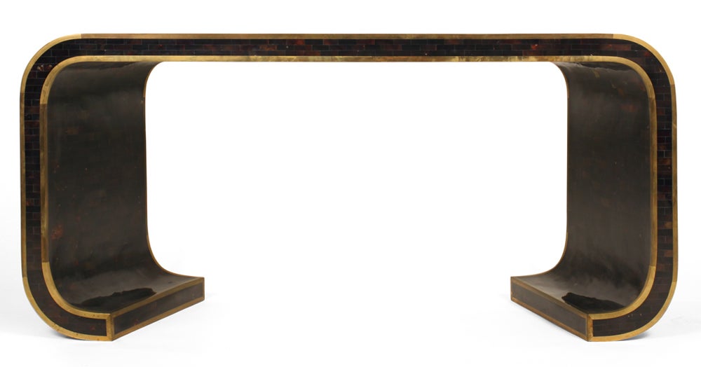An elegant sofa table console in a waterfall form comprising brown penshell tiled veneer and brass band inlay.  The sinuous silhouette is exaggerated by the splayed legs and the concave top edge. Paper label to the underside.  Mod. no. 0019-K7. By