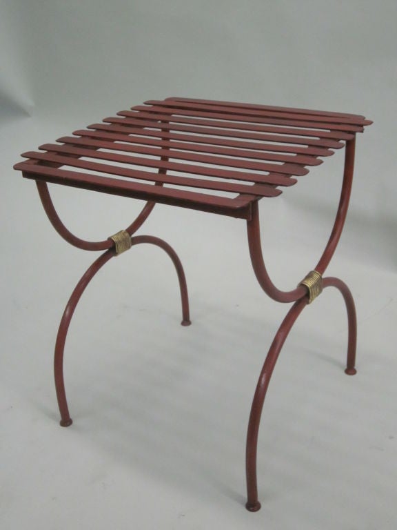 Two elegant pair of French Mid-Century wrought iron curile X-form end tables or luggage racks in the modern neoclassical aesthetic. Each is lacquered Chinese red with gilt iron wrappings uniting the upper and lower parts. It is possible to use these