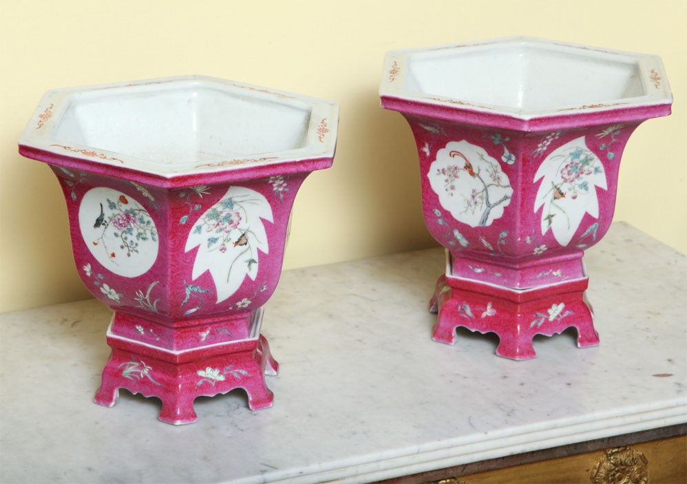 Extraordinary pair of hexagonal jardinieres on conforming stands with bracket feet, decorated with branches and flowers on white leaf shaped reserves with surrounding swirling pink peony ground,with Qianlong marks, late 19th century.