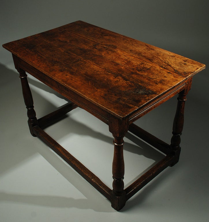A handsome 18th century English elm-wood tavern table with turned legs and stretcher base, sturdy mortise and tenon joinery and a richly colored surface with lustrous patina throughout. The talavera tureen is shown for scale only and is not part of