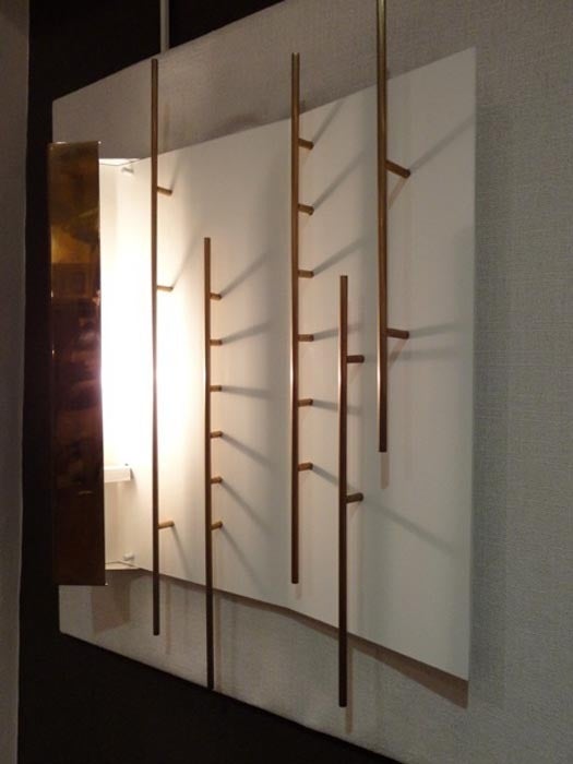 A pair of lit wall sconces each featuring a white lacquered metal back plate with a side c shaped brass compartment that acts as the lamp shade and an abstract brass bar pattern applied to the back plate. By Gio Ponti for Lumi, Italy circa 1960. The