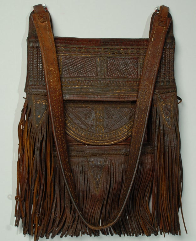 A handsome early to mid 20th century hand tooled leather bag from Fez, Morocco. Three interior pockets, a long braided leather strap and original tassels.<br />
<br />
Dimensions: overall length, including the strap, is 39 inches. The actual bag