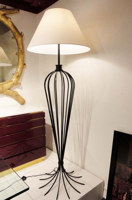 A floor lamp featuring a shaped body in black wrought iron. In the style of Jean Royere, France circa 1950.