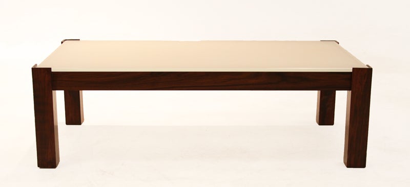 A Brazilian hardwood framed glass coffee table with beautiful graining attributed to Celina Moveis. The legs extend slightly above the glass at the corners which makes the piece even more visually interesting. Glass is rather thick and is reverse