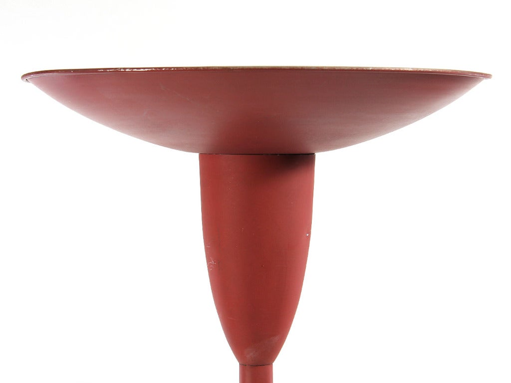 An aluminum torchiere, retaining the original matte red paint, with a shallow bowl-form shade and a domed cast-iron base. 