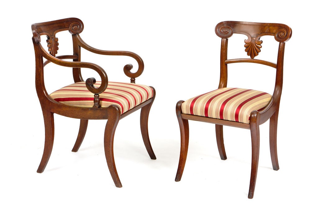 Set of 20 early 19th century Regency mahogany dining chairs. Each with a scroll-carved crestrail over a carved palmette splat and a drop-in seat. Raised on front and back saber legs.

Armchairs:
33 1/2