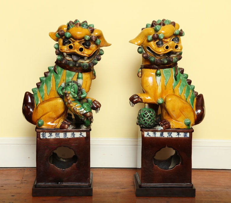 Very fine large pair of polychrome glazed porcelain foo dogs, one female with pup the other male with front paw resting on a movable pierced reticulated ball on stem, decorated in overglaze enamels in brilliant yellows, greens and browns and having