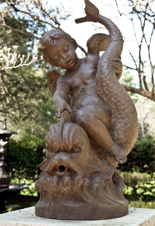A cast-iron fountain group of a cherub on a dolphin attributed to the acclaimed Val d'Osne foundry, dolphin's mouth piped.