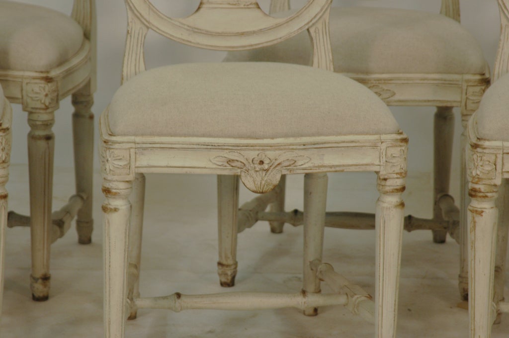 Swedish painted oval back dining chairs from the 1800's. This set of 6 antique dining chairs have shaped seats bowing in the front with carved flowers, the seat is 16 1/2