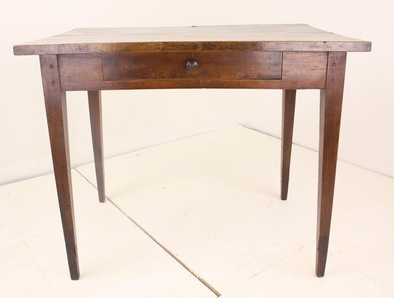 A small antique side table or desk from France. Made of cherry with a beautiful color and patina. Lovely thicker top. One-drawer with small wood knob. Would also work well as a lamp or occasional table. Lovely tapered farm table legs. Good side