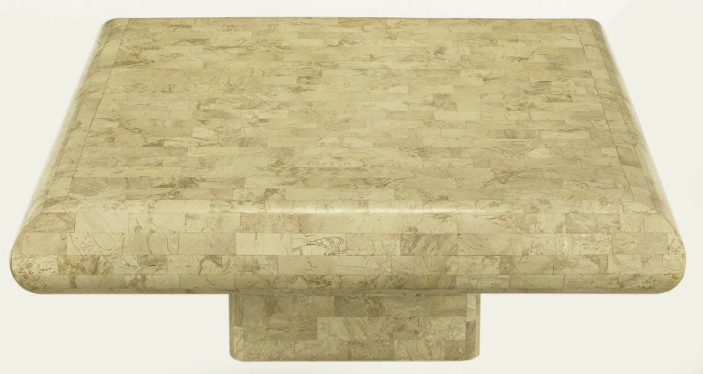 Tessellated fossil stone coffee table with radiused edges and recessed pedestal base. After designs by Karl Springer and Maitland Smith.