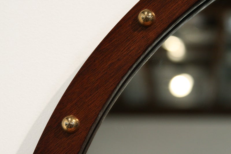 A lovely round mirror in Brazilian exotic hardwood with a clean edge and adorned with polished brass half circles.

Many pieces are stored in our warehouse, so please 