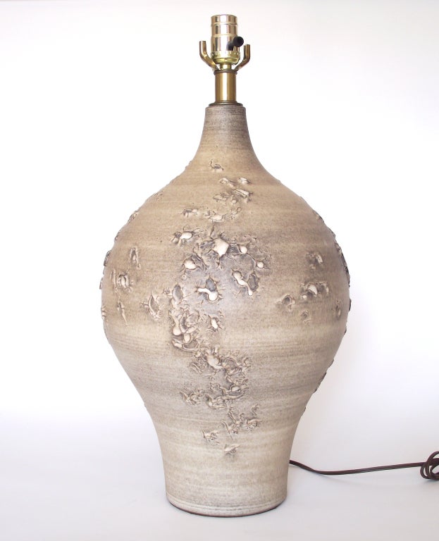 Gorgeous, urn-form ceramic table lamp by Design Technics with a striated, soft matte glaze in shades of cream, sand and mocha and decorated with a highly-textural topographic design that looks particularly stunning when the lamp is illuminated.