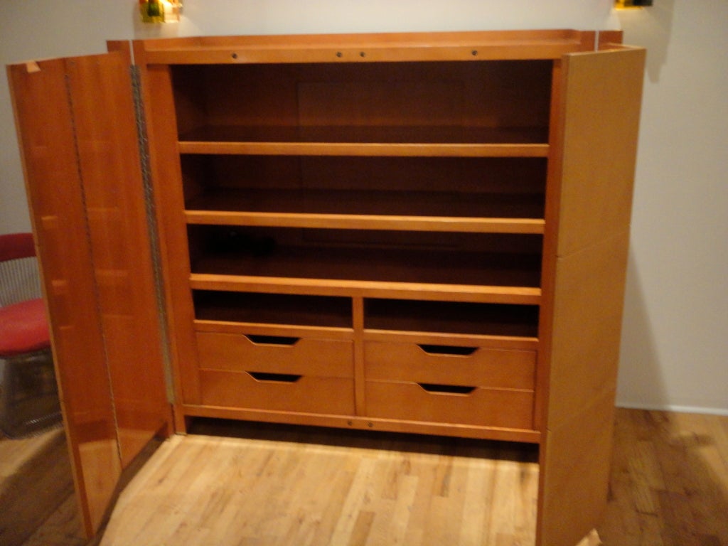 Armoire in stained solid oak two leather doors hidden pull on top that open to reveal  three shelves and four drawers.