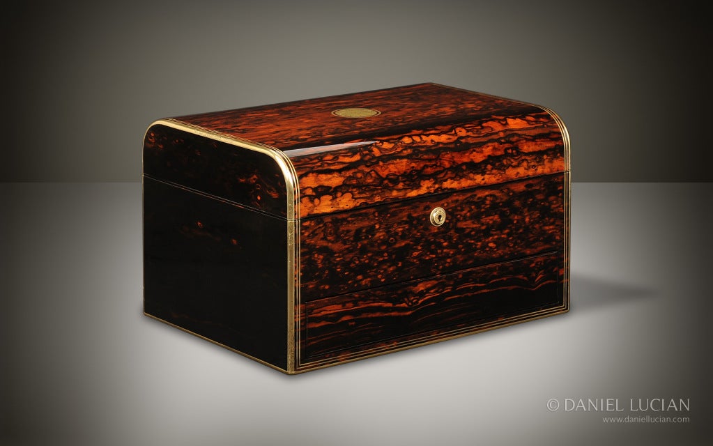 This large English Victorian jewelry box dates from the 1870s. It has a beautifully curved dome-shaped lid, rare in a box of this impressive size.

The exterior is veneered in highly figured coromandel wood with brass binding to the entire