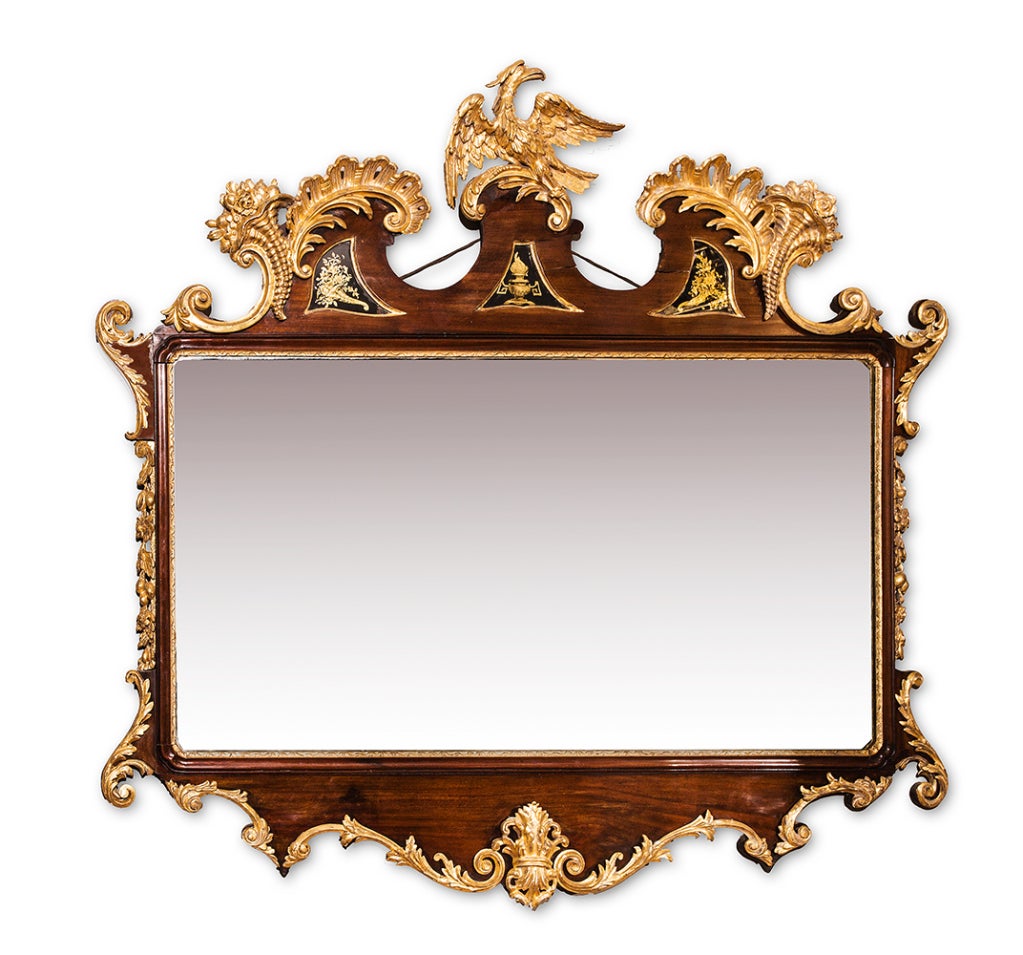 Mahogany and parcel-gilt overmantel mirror. With e´glomise´ panels and an arched cresting centered by a ho ho bird.