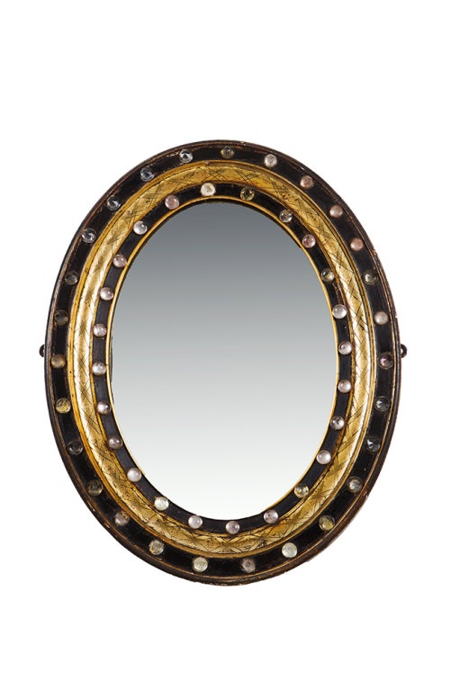 Galway wall mirror.  
the oval mirror plate within concentric bands of ebonized and gilt, the outer and inner bands with applied facetted crystal studs.