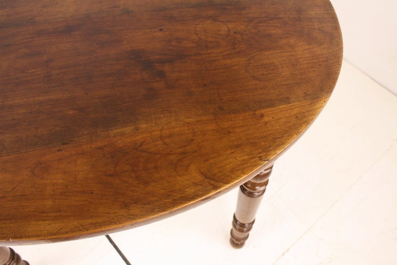 An antique oval table from France with turned legs. This small farm table is made of cherry with beautiful color, graining and patina. Makes a terrific lamp or occasional table. Could be a small breakfast table or center table.