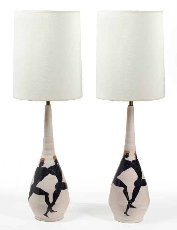 A pair of tall majolica ceramic table lamps, hand thrown and hand-painted with 'Acrobati' acrobat figures in black on a white glazed ground. Each signed to the base. By Ernestine, Salerno, Italy. Italy, 1954.