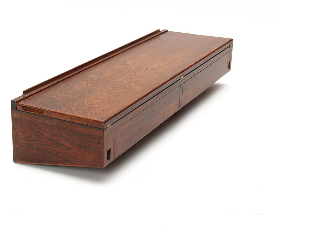 A wall mounted rosewood flip-top desk, with a black laminate writing surface over a pair of drawers.