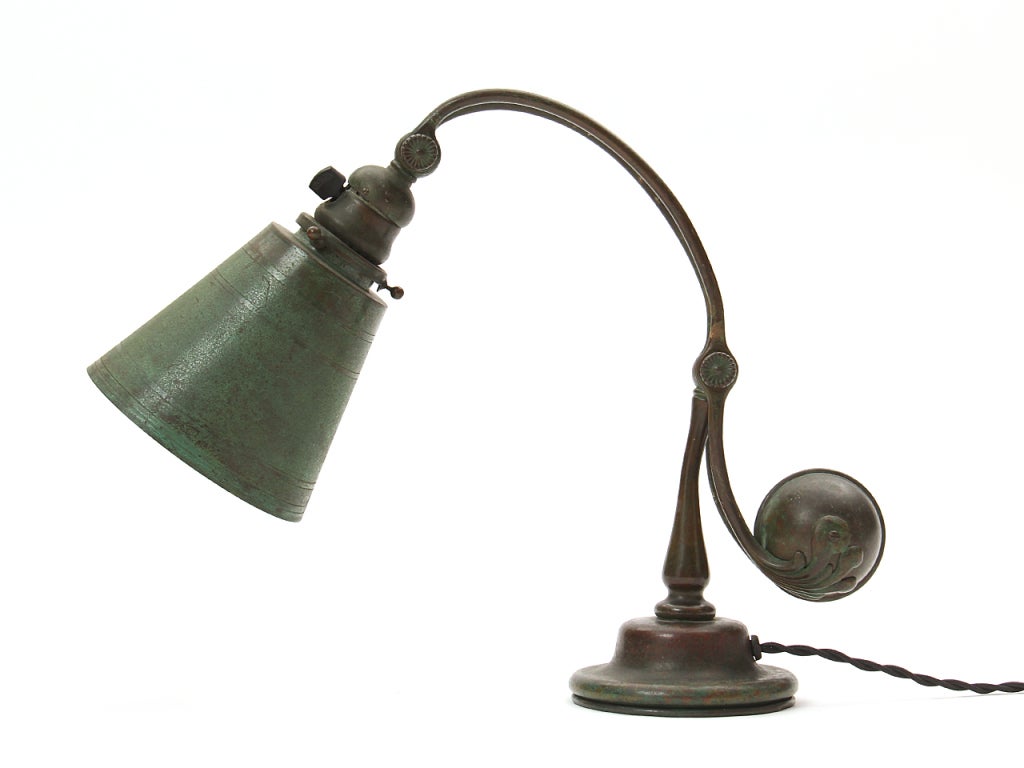 A bronze desk lamp with articulating arm and counterweight having a verdigris patina shade