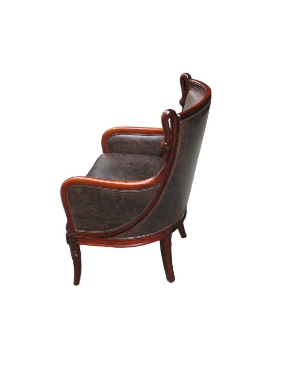 Pair of outstandingly designed and detailed South German barrel back Biedermeier bergères or club chairs. French Directoire-inspired. Looped swans. Wood carved rosettes and palmettes. Saber legs. Mahogany. Reupholstered with loose cushion seats and