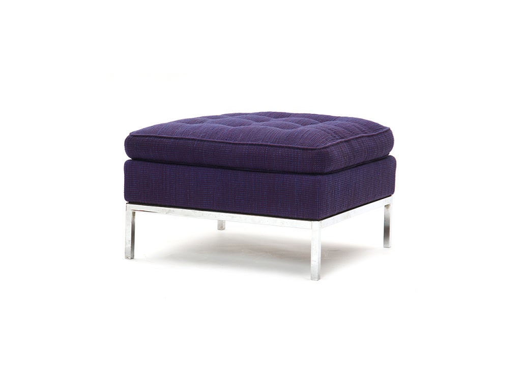 A simple square ottoman with a chromed base and the original purple upholstery.
