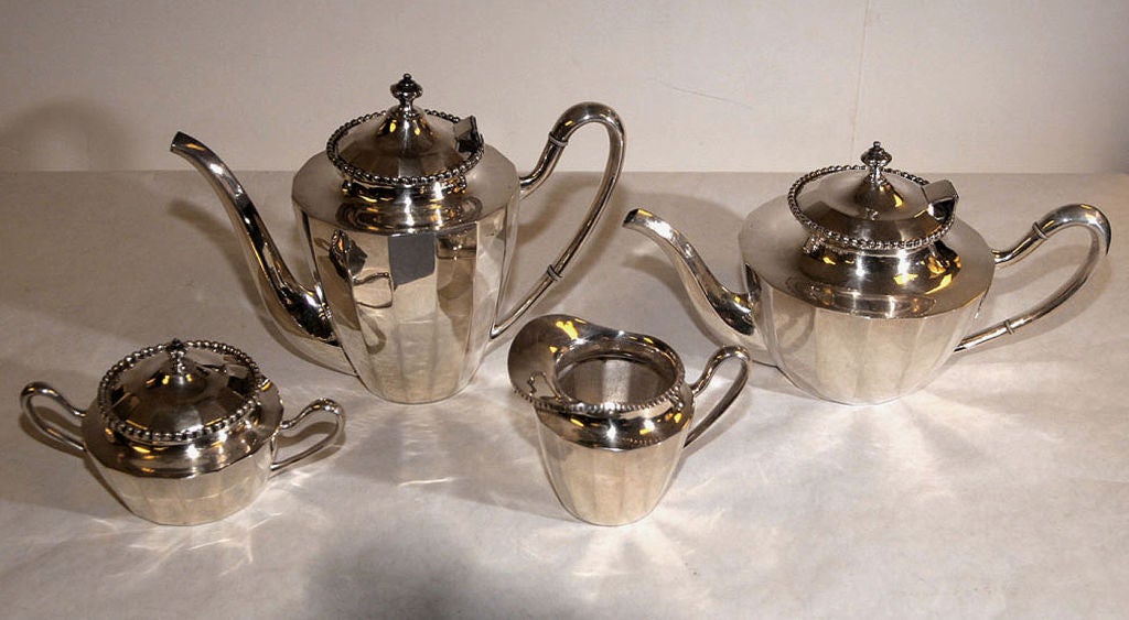 IN THE ART DECO STYLE, COMPRISED OF TEAPOT, COFFEE POT, CREAMER AND SUGAR BOWL, EACH PARTLY FACETED PIECE WITH LOOP HANDLE AND BEADED BORDER, THE LIDS WITH QUATREFOIL URN FINIALS. FULLY MARKED. WEIGHT: 92oz 