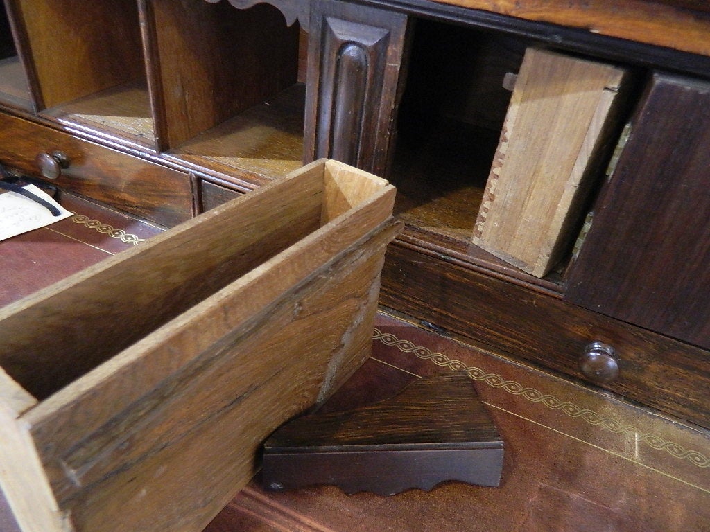 Important Anglo-Indian secretary bookcase with campaign hardware. It has a soft fragrance when it is opened from the rosewood. The top has two sunburst carved doors with two interior shelves and an elaborate carved cornice. The base has a  top