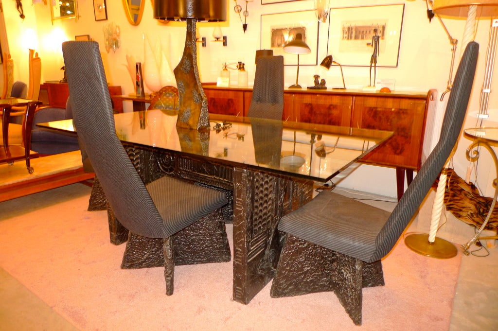 The brutalist design of the table base & chairs is made of a bronze resin substance in the manner of Paul Evans and Swiss surrealist H R Giger.  Produced by Craft Associated in 1972.

This is the more desirable black tone bronze resin 