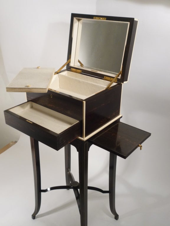 Art Deco Macassar Ebony Travelling Cabinet on stand with ivory stringing and fitted interior, by Mappin & Webb, Including four silver top scent bottles. Hallmark- English silver, 1909, makers George Betjenmann & Sons.
The inside of the lid is