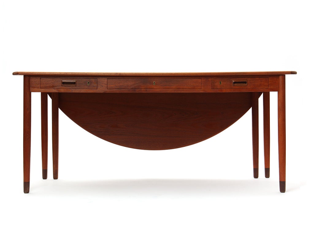 A rectangular teak executive desk with a demi-lune drop leaf.