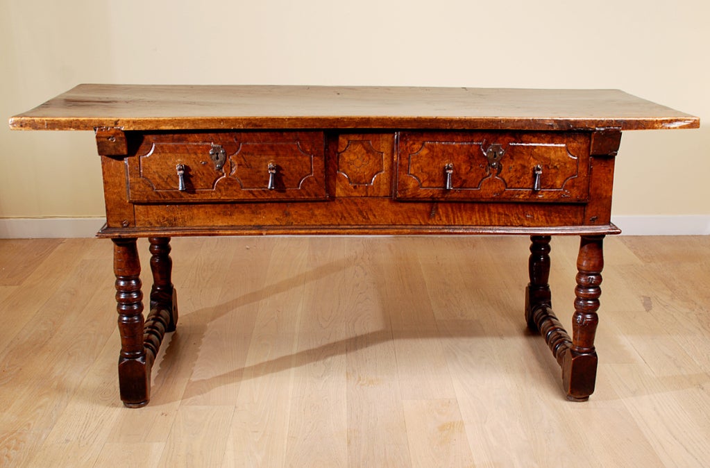 A superb 17th century Spanish Baroque period walnut table with large single plank top over two carved drawers -- raised on turned legs terminating into block feet. 

Dimensions: 68 inches wide x 28.5 inches deep x 31.5 inches high.