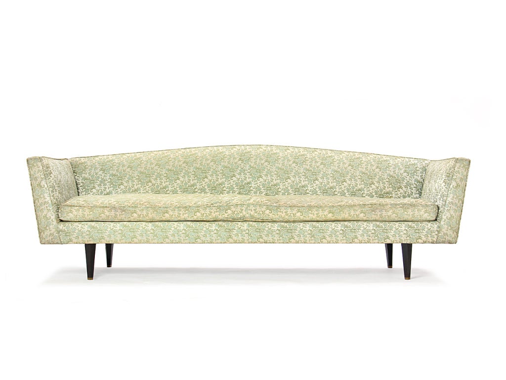 A rare upholstered sofa with an arched back on pentagonal shaped mahogany legs.