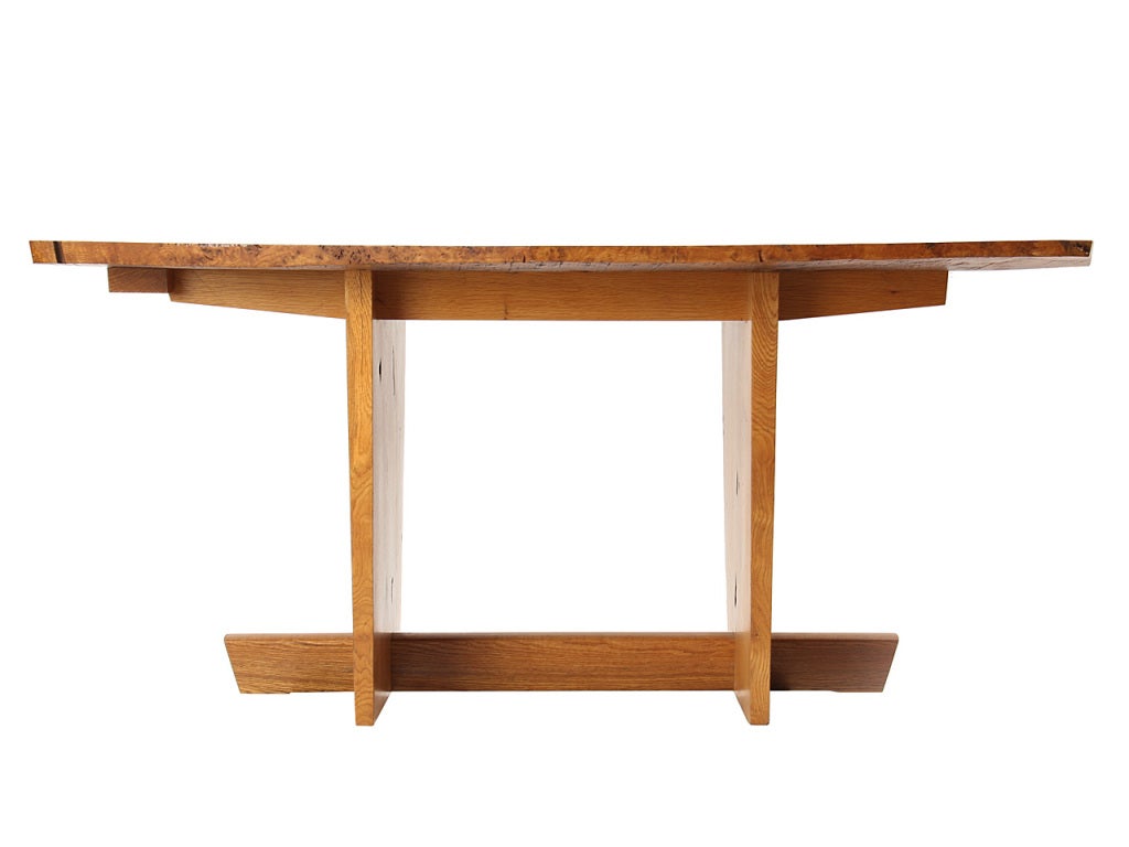 A burled oak table with a large butterfly stabilizer and oak trestle supports. Design and drawings for this special table were done by George Nakashima; the table was signed and executed by Mira Nakashima.