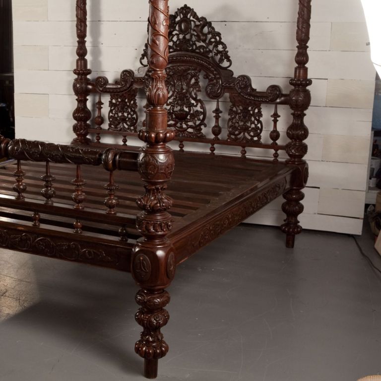 Elaborately carved Anglo-Indian four poster bed with cornice. Headboard has coat of arms carving. Bed has original patina. Would fit a mattress 67