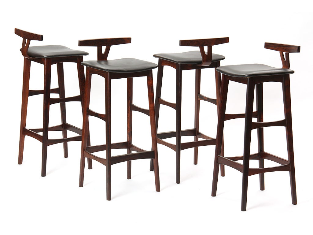 A set of four rosewood and black leather stools with low wishbone back design. Priced as set.