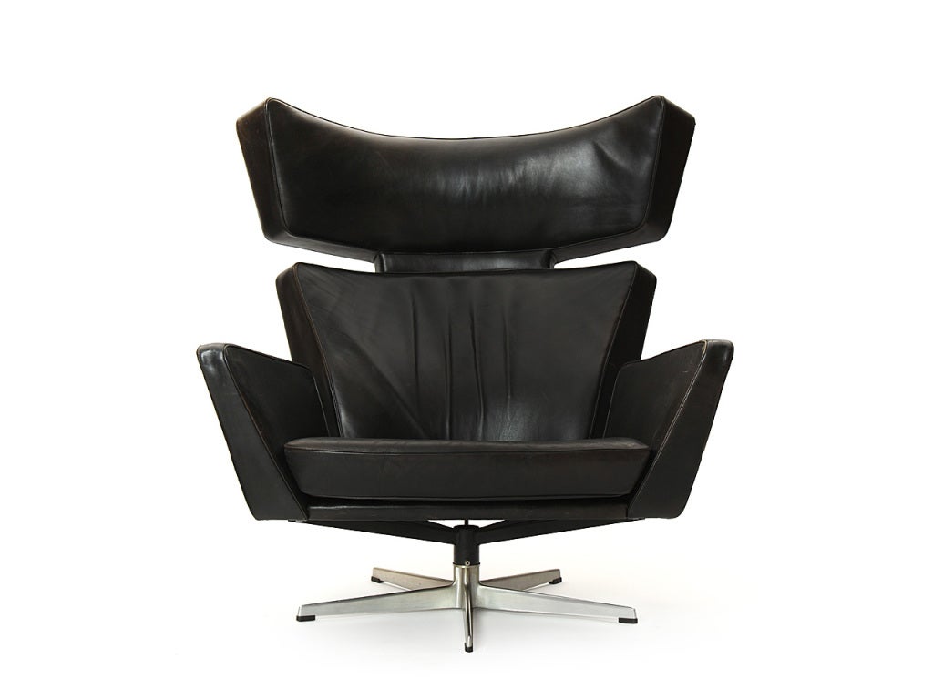 A fine and uncommon Ox chair, its strong and expressive form retaining its original rich oiled black leather and floating above a cast aluminum five point base. Designed by Arne Jacobsen and manufactured by Fritz Hansen.
