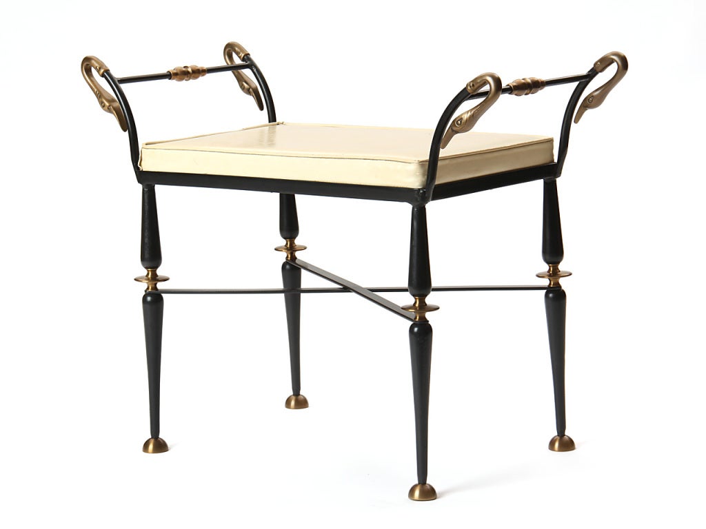 A black cast-iron Swan neck bench with brass finishes and a thin upholstered cushion.