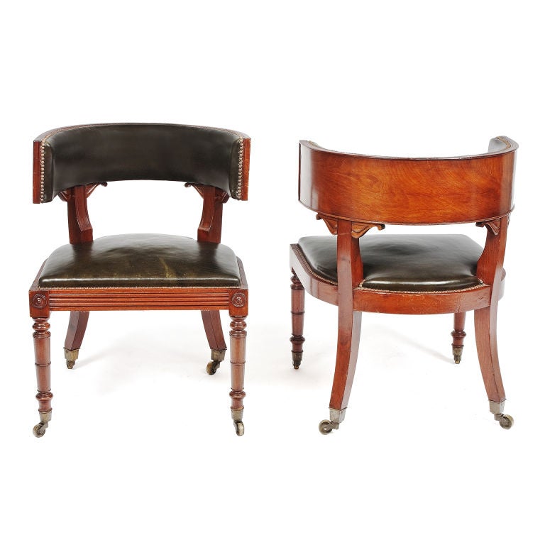 An exceptional pair of regency cove back mahogany library chairs, the backs being of figured mahogany with carved scroll brackets,  the lathe turned tapering front legs surmounted by round paterae linked by reeded front seat rail and having sabre