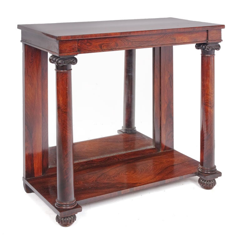 Console table with moulded and shaped top above two iconic columns to the front and a mirror plate to the rear on a base shelf on gadroonned bun feet.