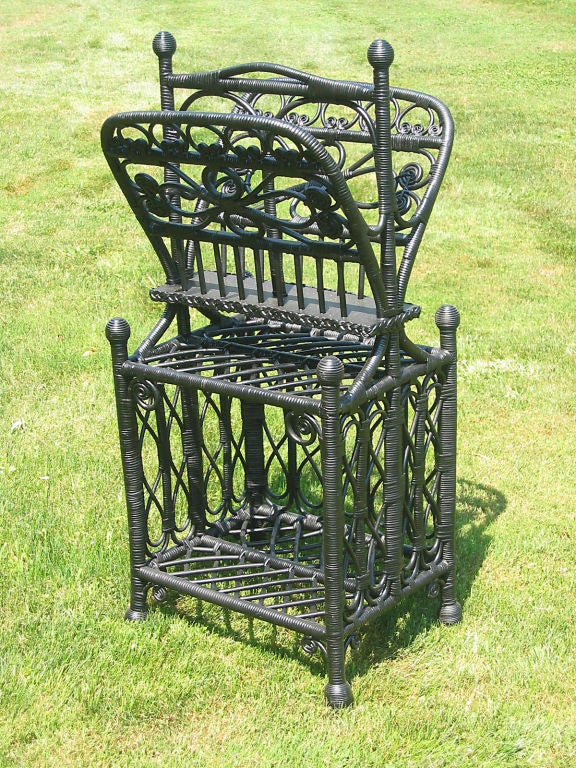 Fancy Victorian wicker canterbury in black painted finish. Upper half with sectioned portfolio, open storage in lower half. Multiple curlicues and woven loops.